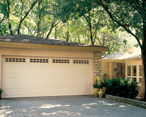Suburban house with a beige two-car garage and tree-shaded driveway
