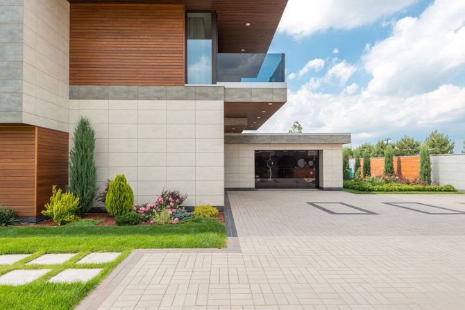 Modern house exterior with wood accents, balcony, driveway, and landscaped front yard