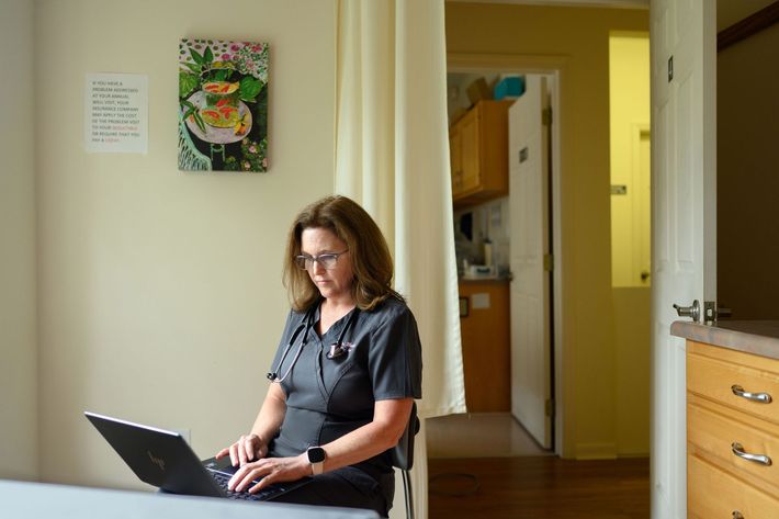 A woman is sitting at a table using a laptop computer.
