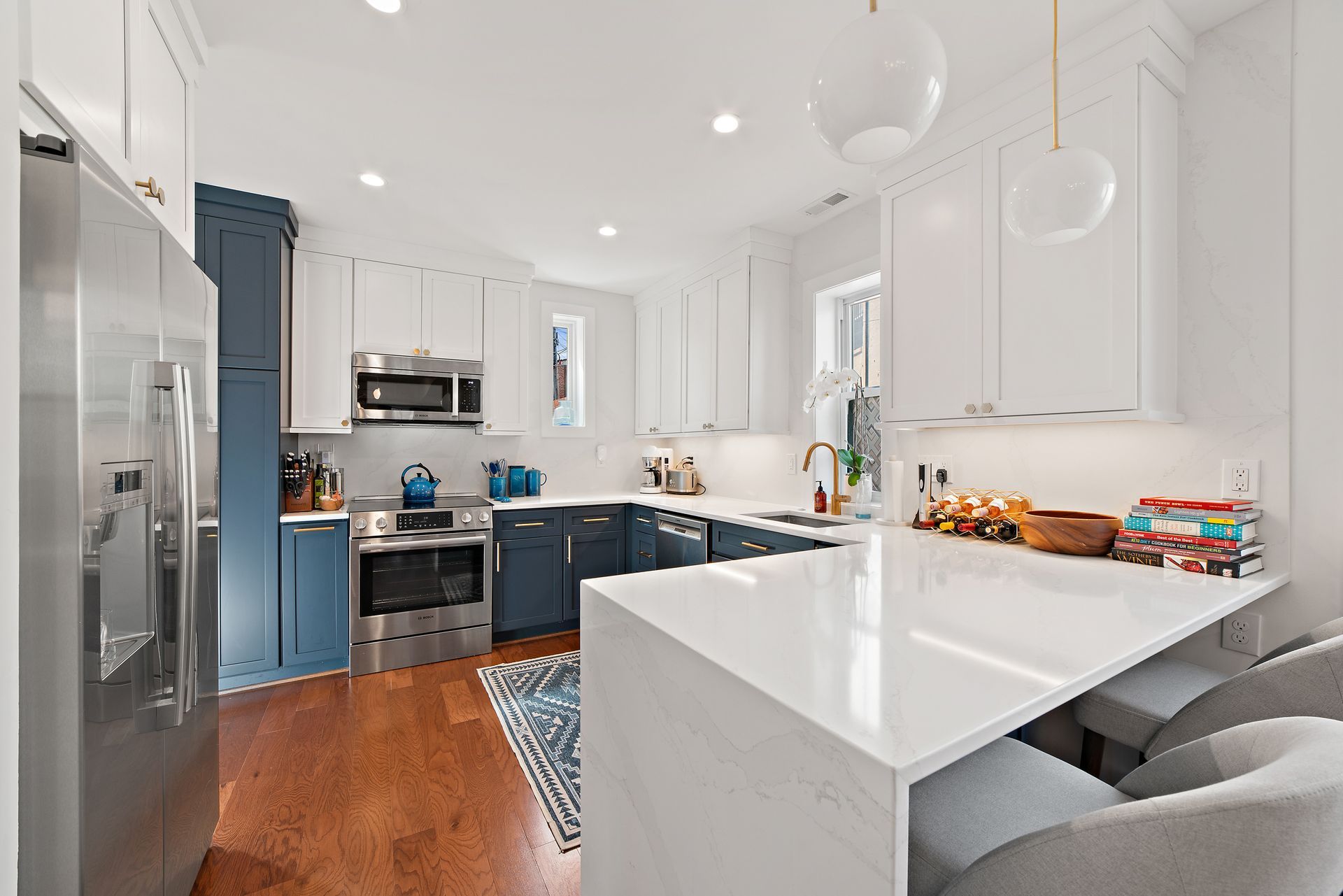 Navy and white kitchen with waterfall island, quartz counters, gold fixtures, and shaker cabinets in DC home renovation