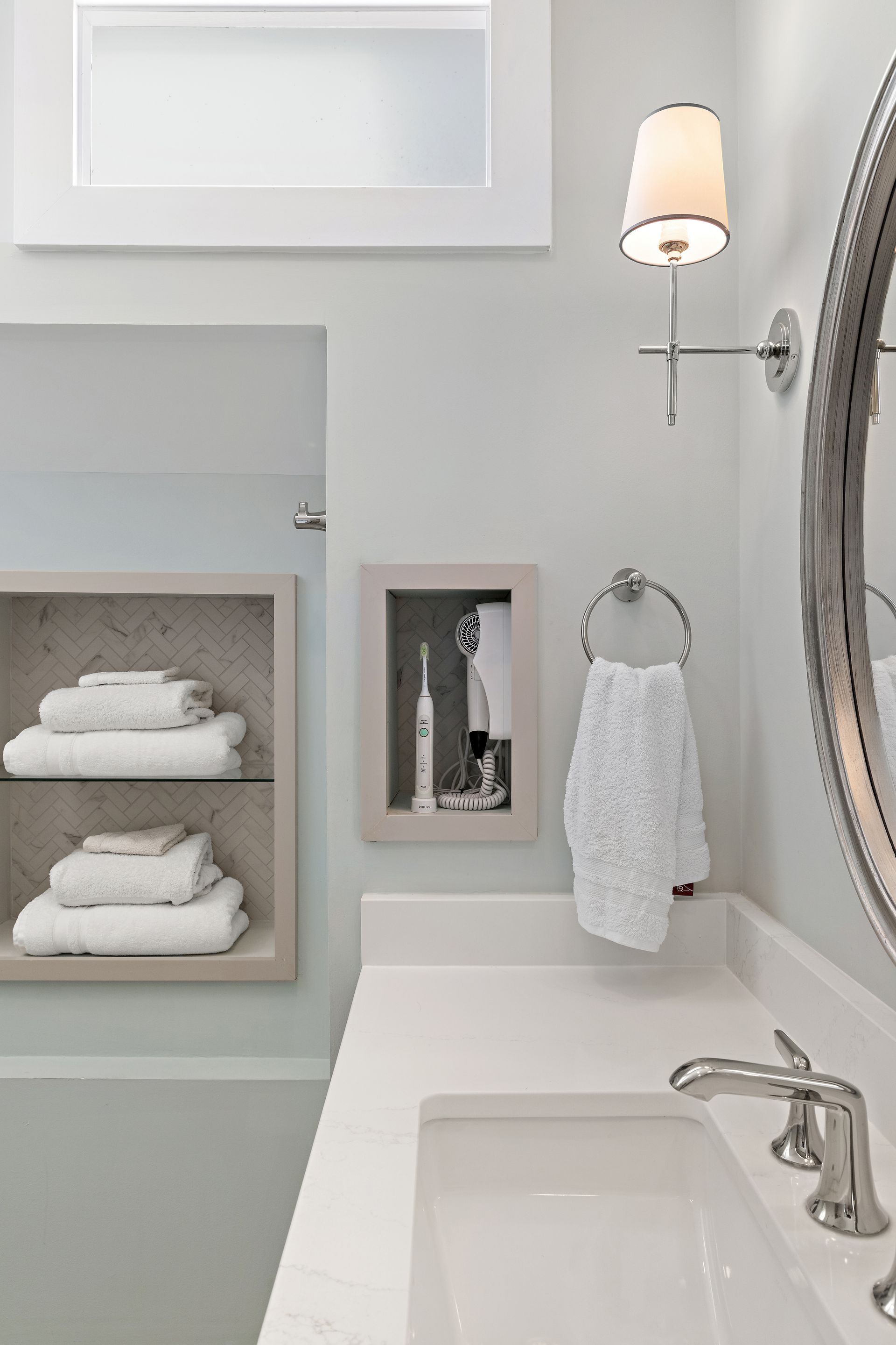 Neutral bathroom vanity with quartz counter, towel shelf niche, and built-in appliance cubby