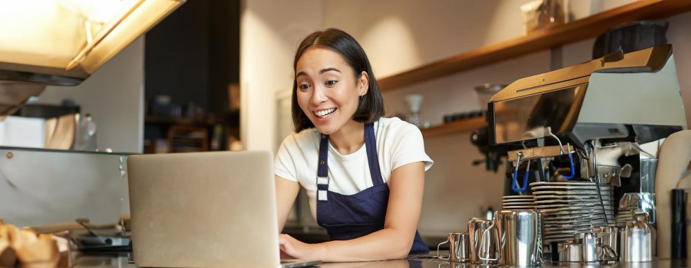 A woman is sitting at a counter using a laptop computer.