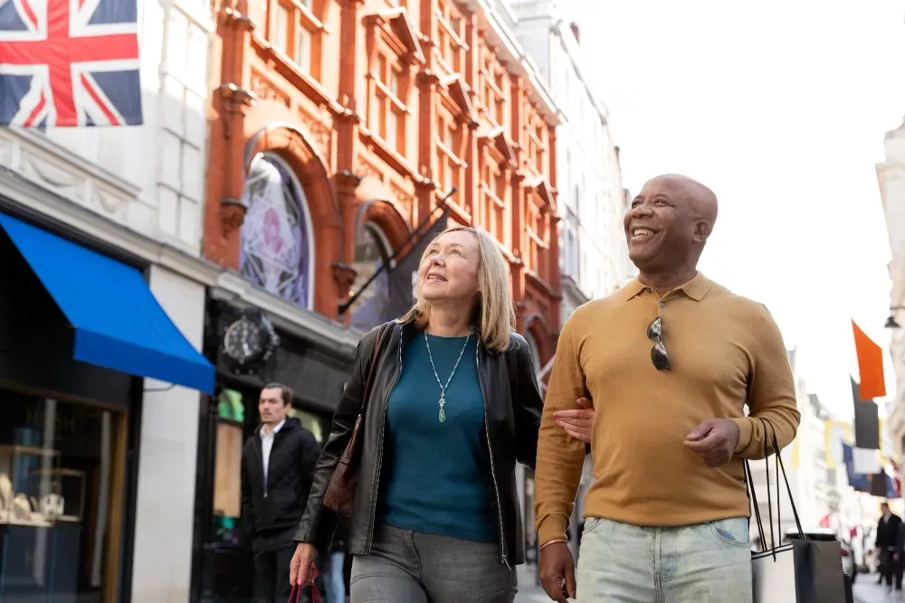 A man and a woman are walking down a city street holding hands.