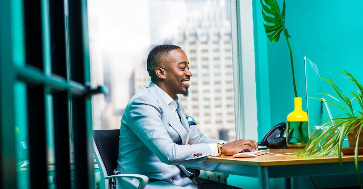 A man in a suit is sitting at a desk in front of a computer.