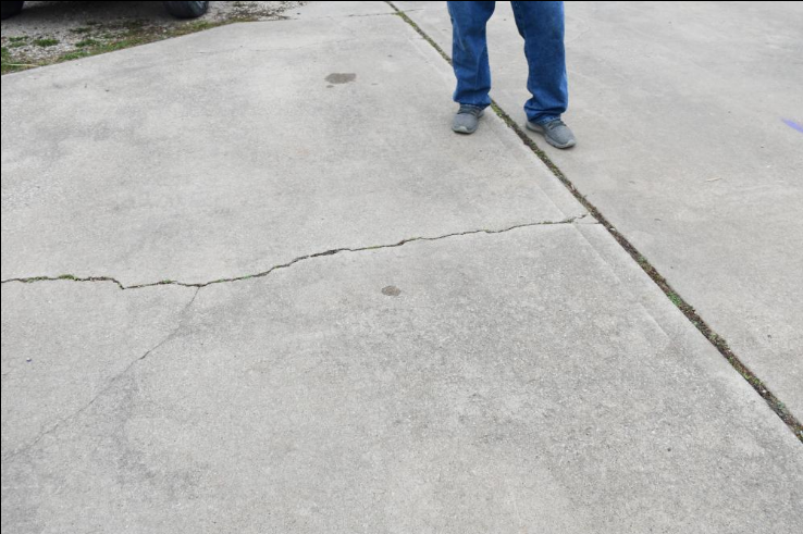 Worker filling a crack in a concrete slab with repair compound on a Four Corners FL driveway