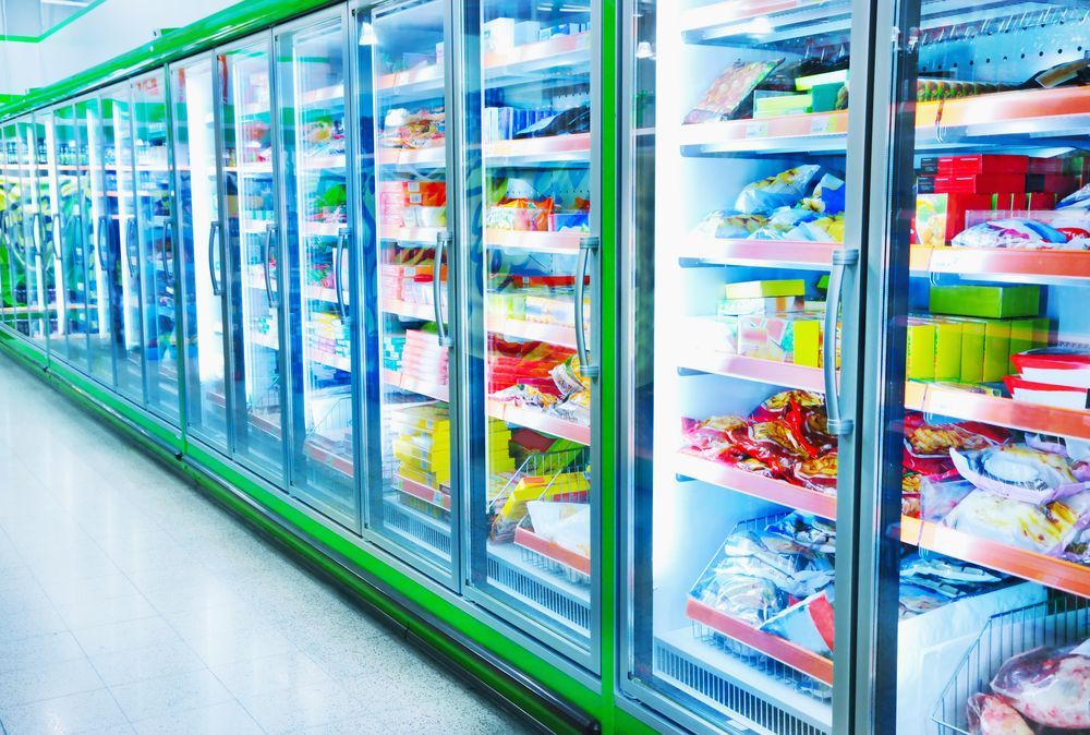 A Row Of Illuminated Freezers In A Grocery Store, Filled With Frozen Food — Ace Fridge Door Seals in Cairns, QLD
