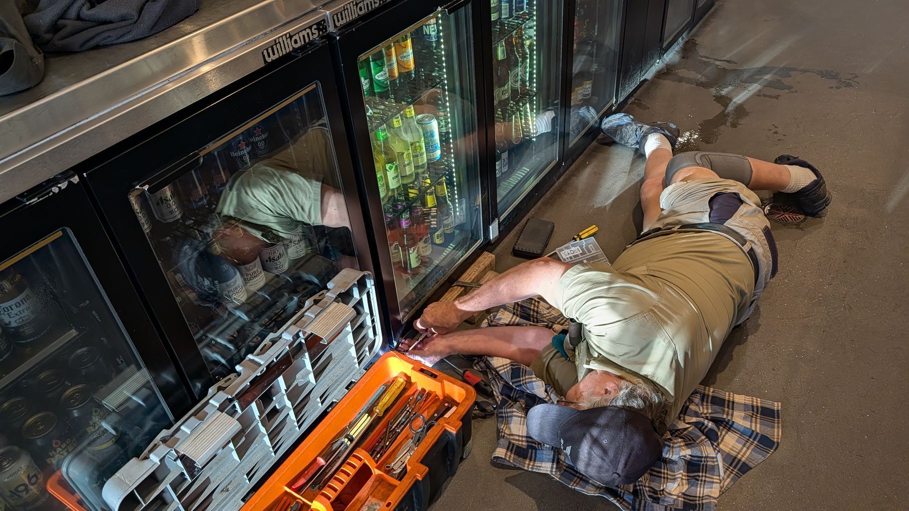 Person Lying on a Checkered Mat Beside Glass-door Coolers — Ace Fridge Door Seals In Cairns, QLD
