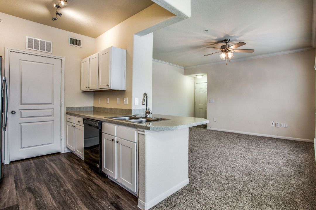 Open-concept kitchen with white cabinets, island sink, and adjacent living area.