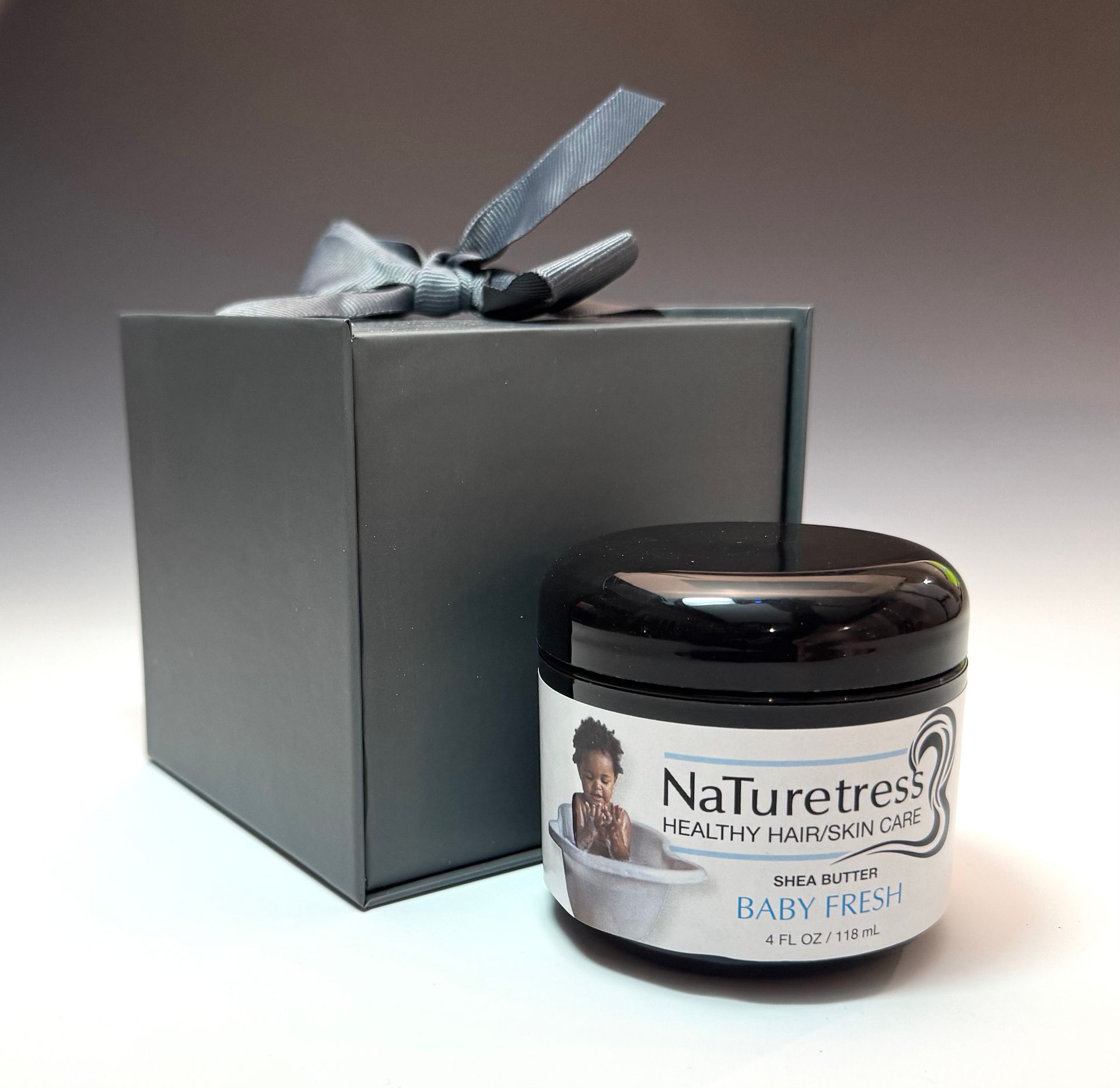 Black box with gray ribbon next to a jar of