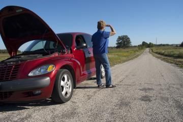 Red car with hood up, stranded on a rural road; person looking toward the sky appears to be stranded.