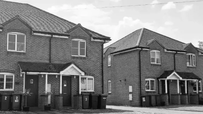 A black and white photo of a row of brick houses.