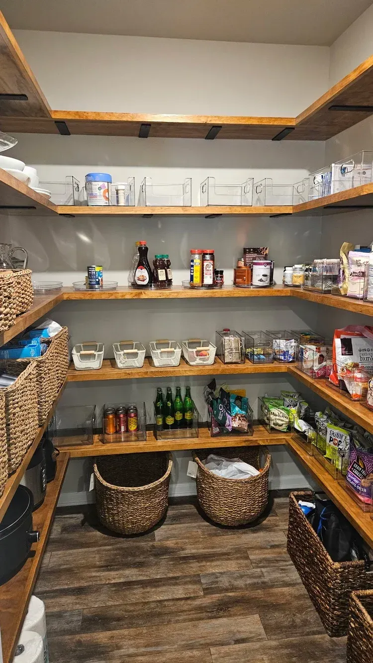 A well-stocked pantry with wooden shelves and baskets filled with food items.