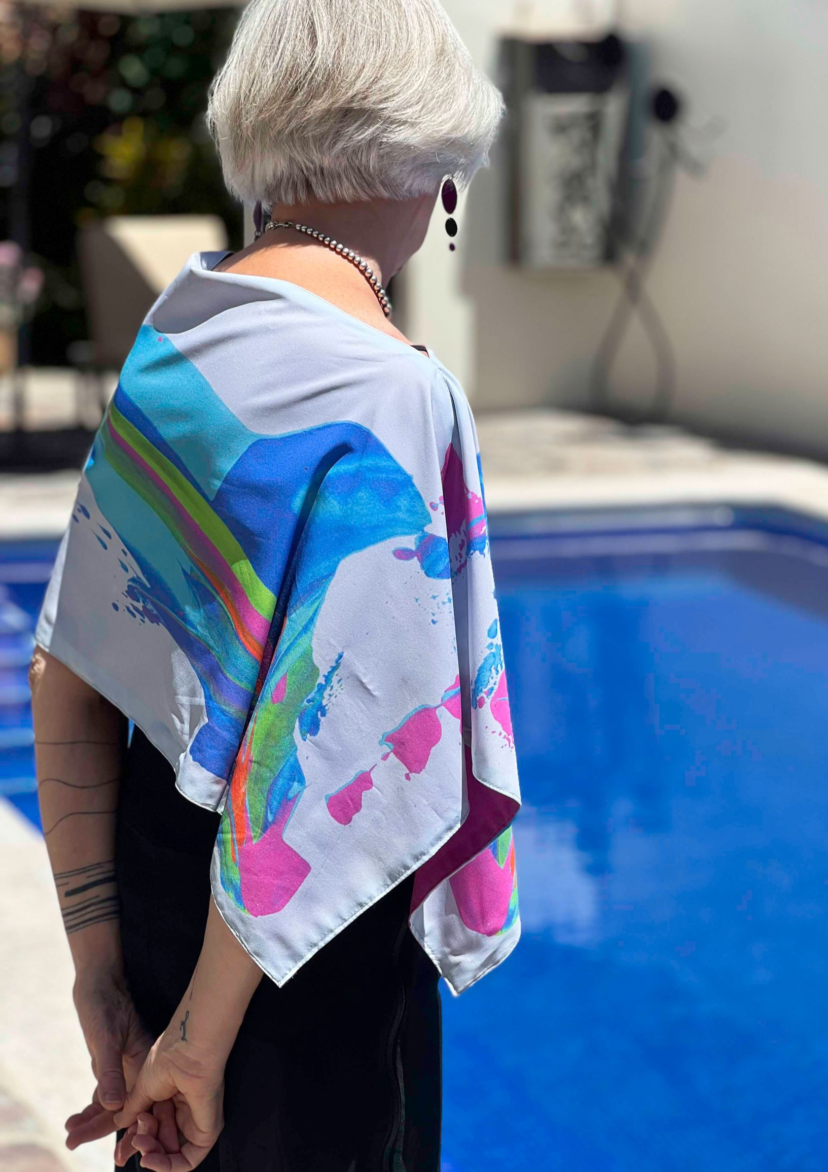 Person wearing colorful scarf by a pool.