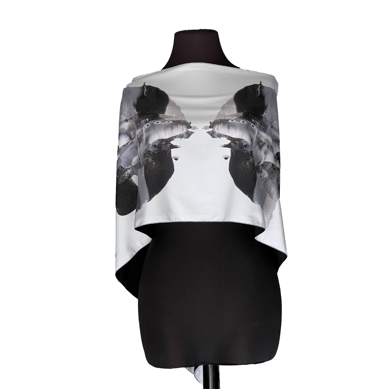 Black dress form wearing a white draped top with dark abstract floral prints