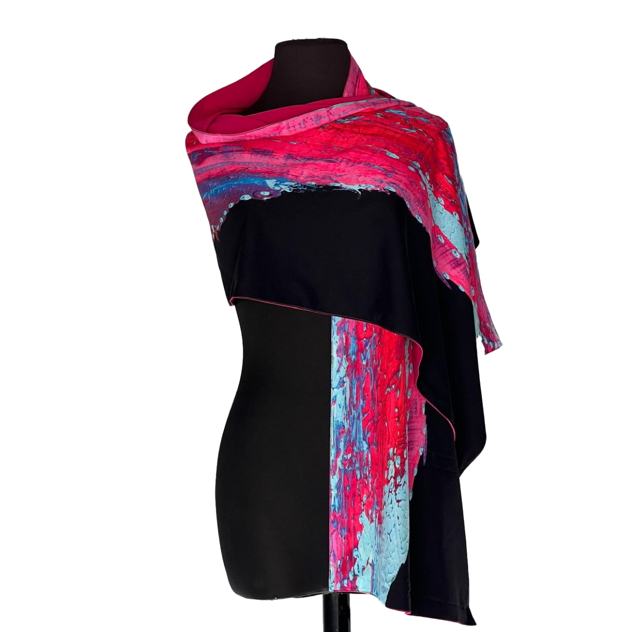 Black mannequin wearing a vibrant pink, blue, and black draped shawl scarf