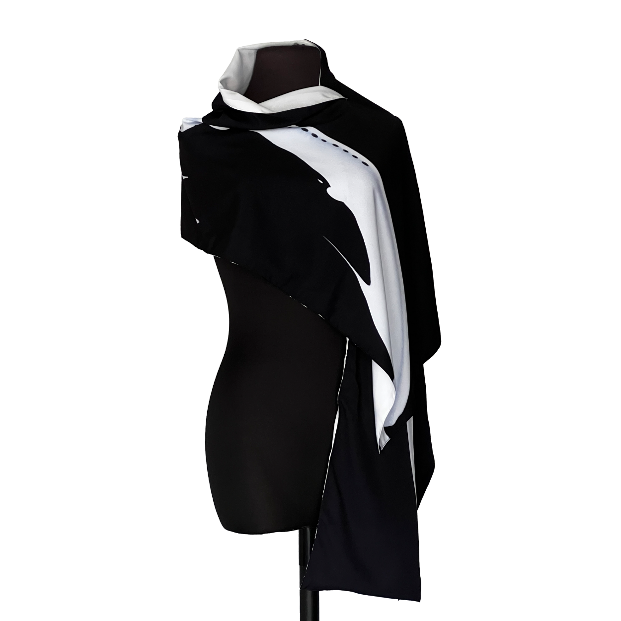 Black and white scarf draped over a black mannequin, with a white abstract design.