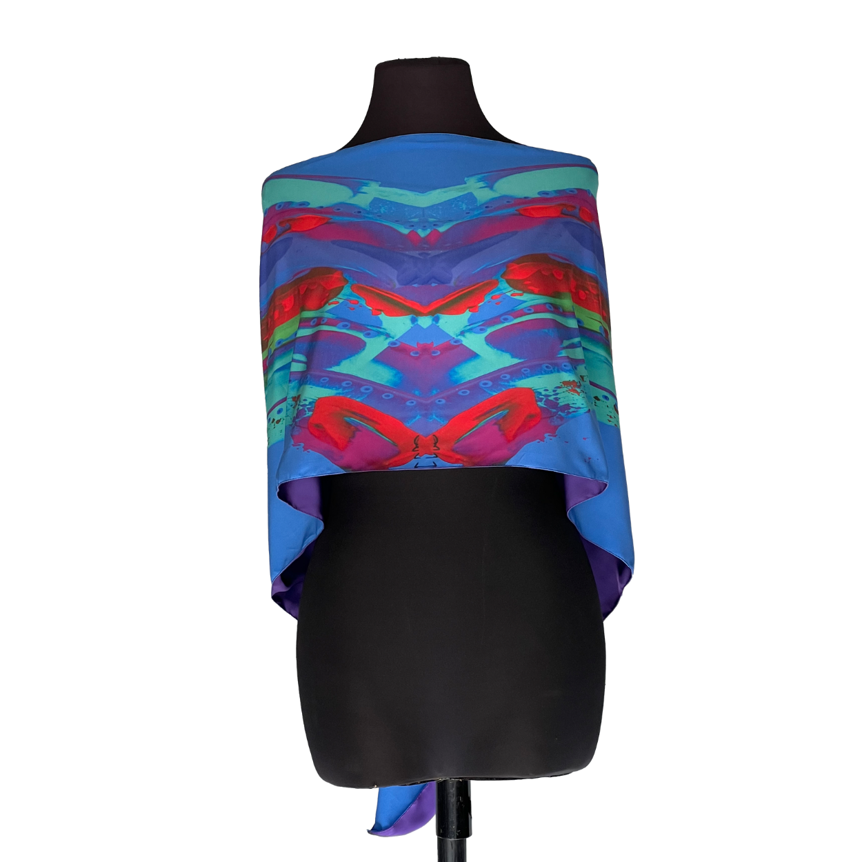 Black mannequin wearing a colorful blue, pink, and purple patterned shawl