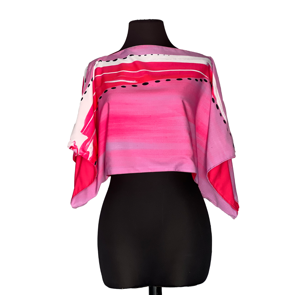 Pink, cropped silk poncho on black mannequin. Features abstract watercolor-like design in various shades of pink.