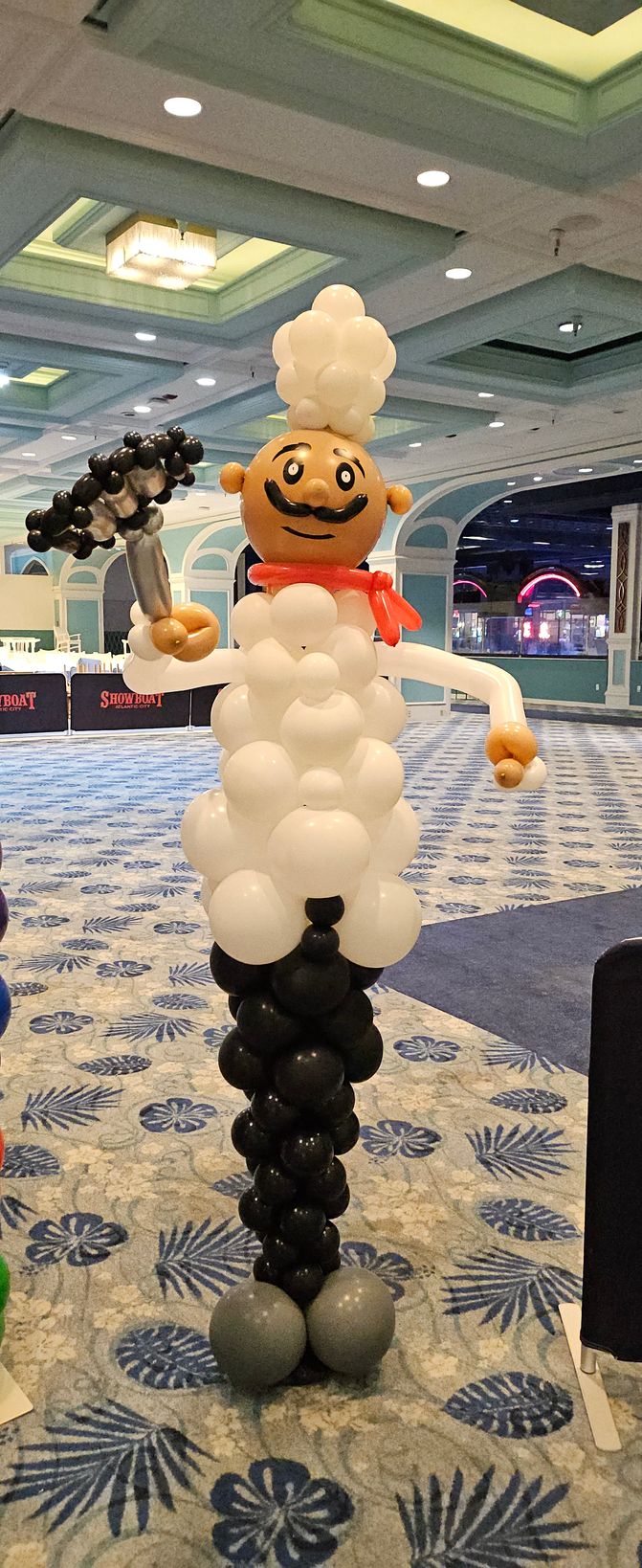 Life-size balloon chef sculpture created by My Life In Balloons LLC for the Let’s Get Cookin’ 25 event at Showboat Casino in Atlantic City, NJ. Features white chef hat, mustache, red scarf, and balloon whisk.