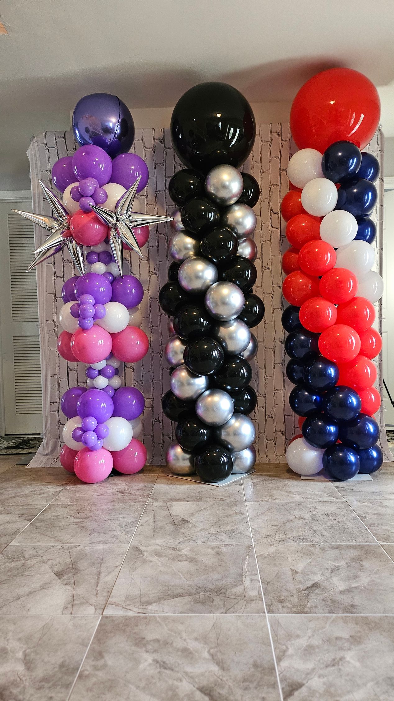 Set of three balloon columns by My Life In Balloons LLC featuring starburst accents, chrome balloons, and a red-white-blue patriotic design.