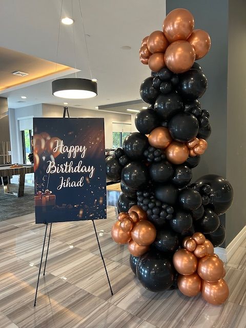 Luxury black and copper balloon garland by My Life In Balloons LLC for a birthday party celebration. Features chrome copper accents and custom styling beside a birthday sign.