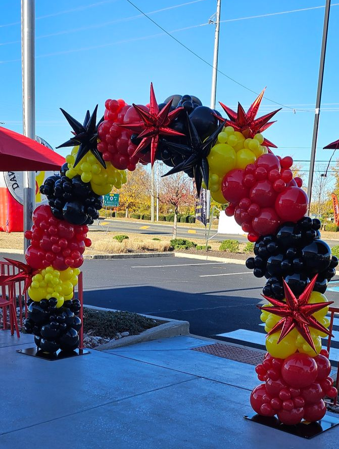 Balloon arch in red, yellow, and black created for Dave’s Hot Chicken grand opening, featuring spiked starburst foil balloons and clustered balloon textures.