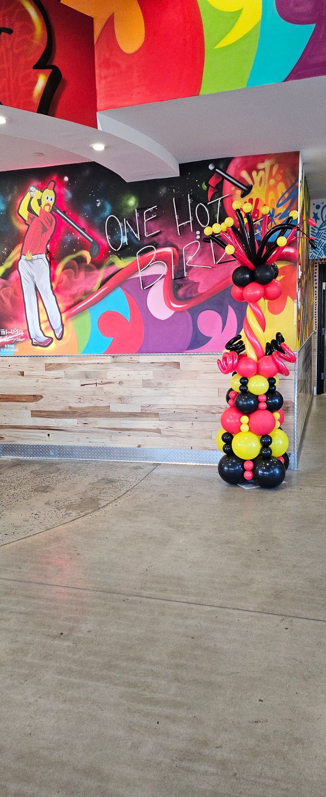 Bold balloon tower for Dave’s Hot Chicken grand opening, featuring red, yellow, and black spirals, oversized topper spikes, and dramatic curls, created by My Life In Balloons LLC.