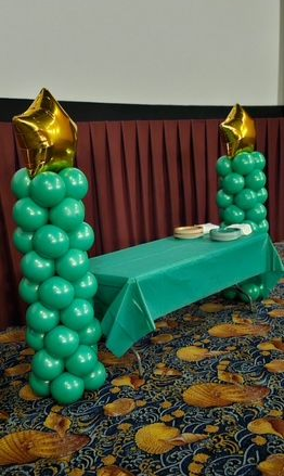 Green balloon columns with gold foil star toppers decorating a table at TD Bank’s Wild Stars event.