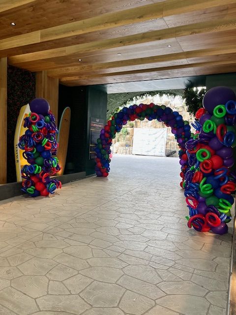 Multicolor balloon arch and colorful swirl towers at Island Waterpark entrance for Let’s Get Cookin’ 2024 by My Life In Balloons LLC.