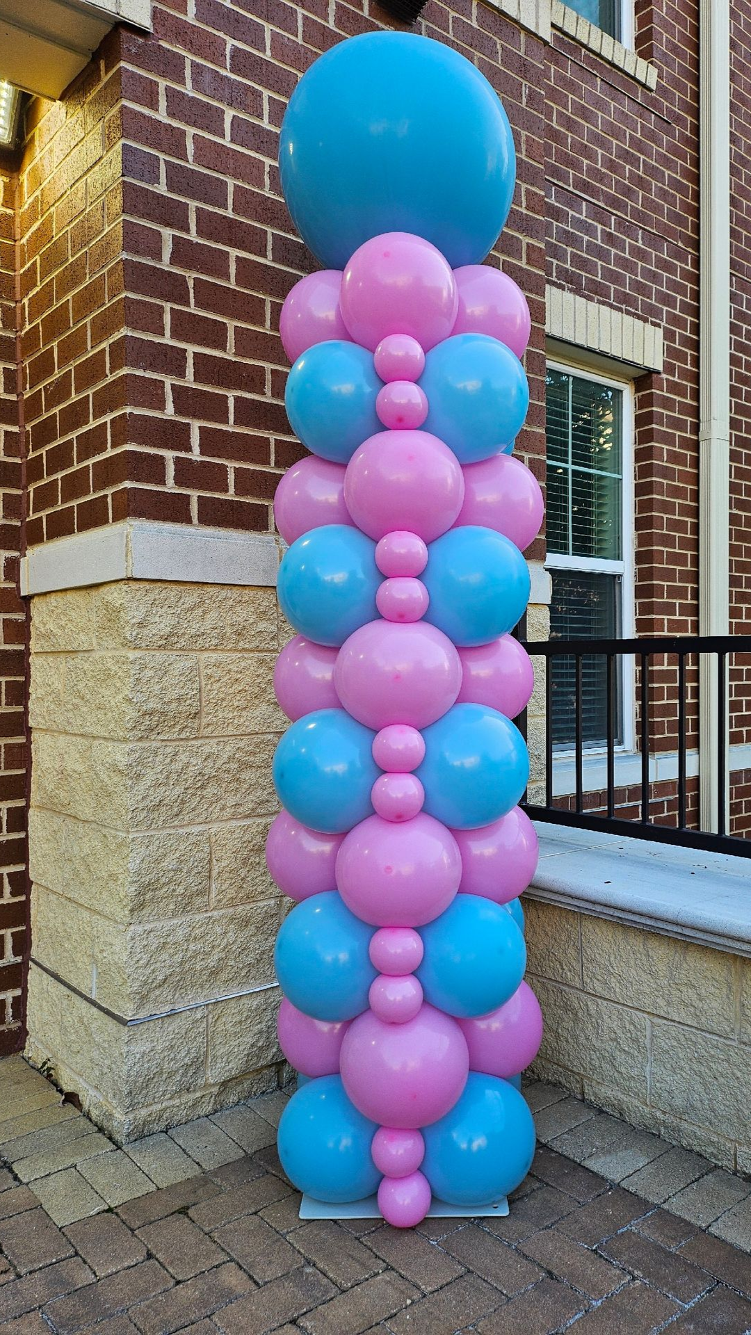 Pink and blue balloon column created by My Life In Balloons LLC. Features layered balloon sizes with a large topper, ideal for baby showers, gender reveals, or brand-themed corporate events.