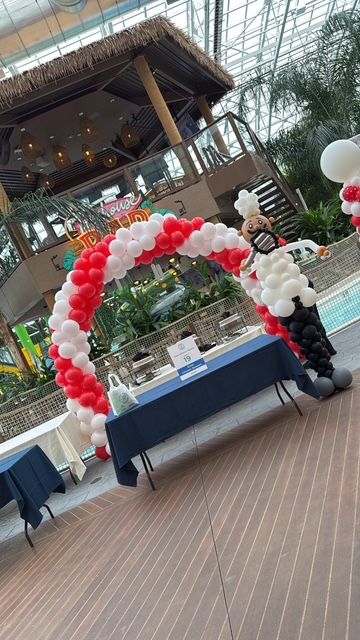 Red and white open balloon arch with chef balloon sculpture by My Life In Balloons LLC for Let’s Get Cookin’ 2025 at Showboat Waterpark.