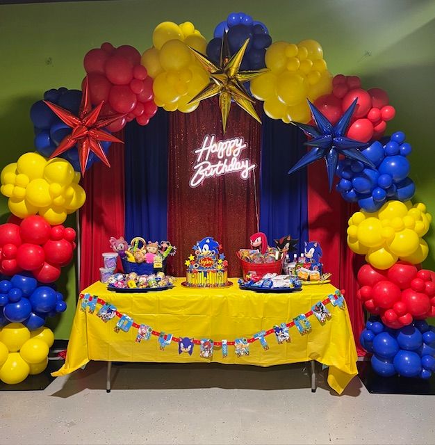 Sonic the Hedgehog balloon backdrop at Fun City Turnersville, NJ by My Life In Balloons LLC, featuring red, yellow, and blue balloon garlands with metallic starbursts and themed treat table.