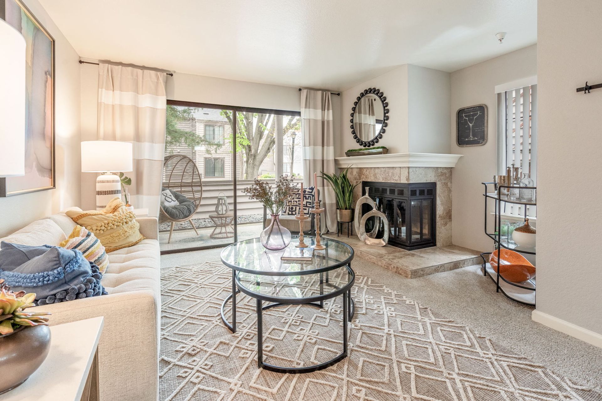 Living room with beige sofa, glass coffee table, fireplace, and sliding balcony door at Hidden Lake apartments in Sacramento, CA.