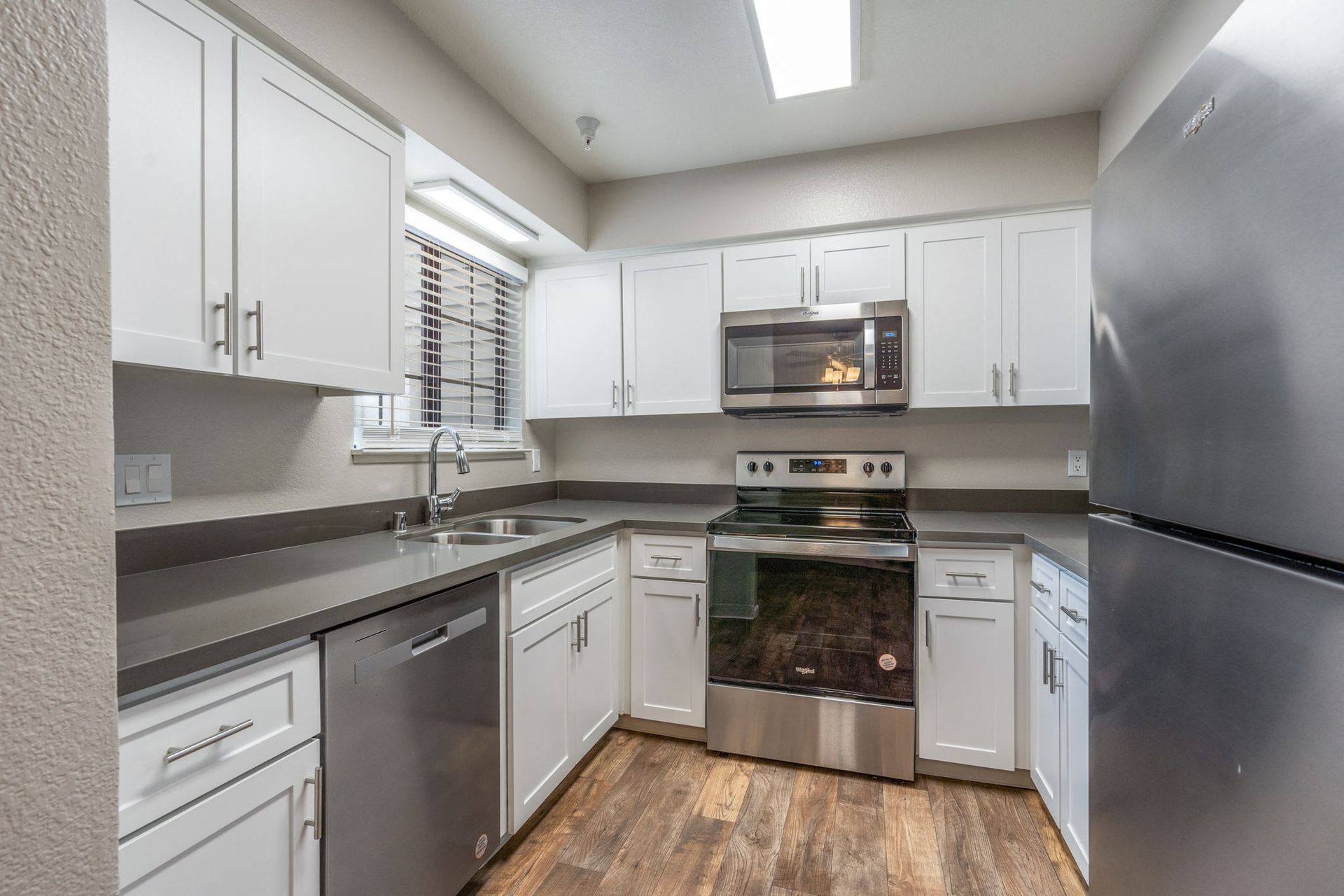 Modern kitchen with white cabinets, stainless steel appliances, and a double sink at Hidden Lake apartments in Sacramento, CA.
