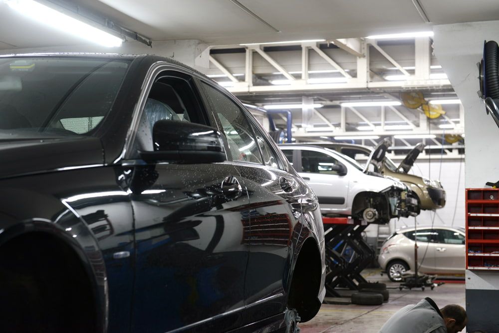 A Black Car Is Parked in A Garage with Other Cars — Tweed Exhaust & Mechanical In Tweed Heads South, NSW