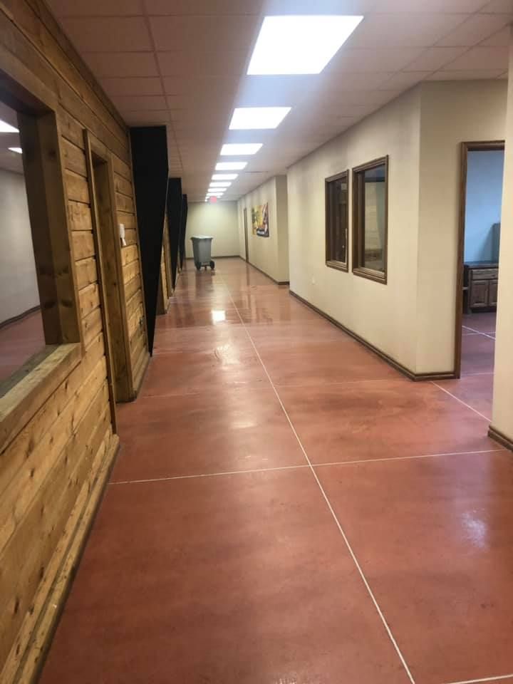 Hallway with red floor and doors, featuring wood paneling and a trash can.