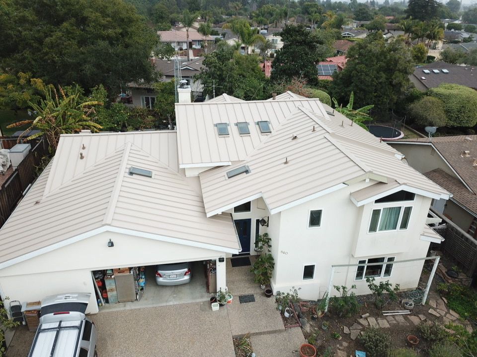 An aerial view of a large white house with a tan roof
