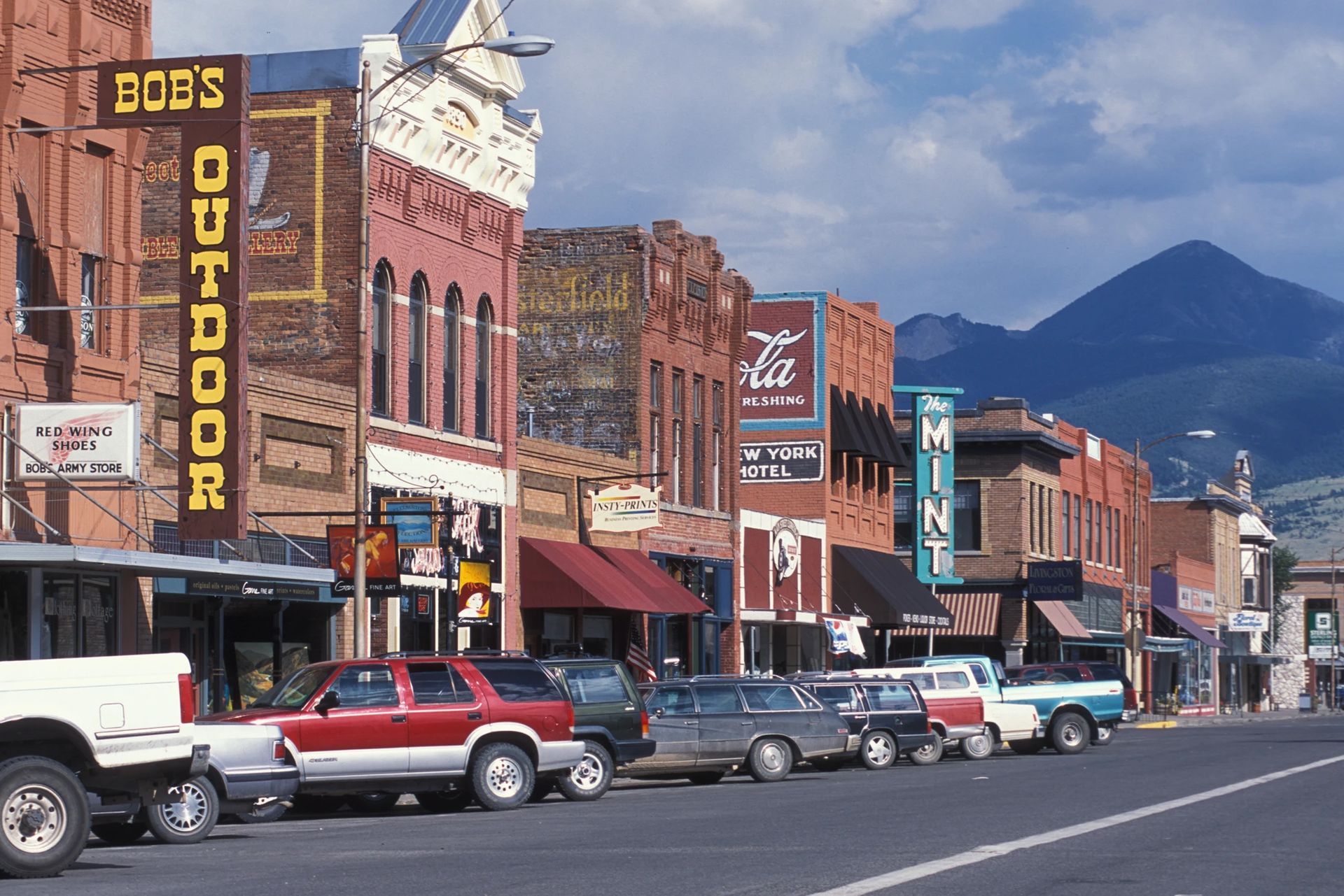 A row of cars are parked in front of bob 's outdoor store