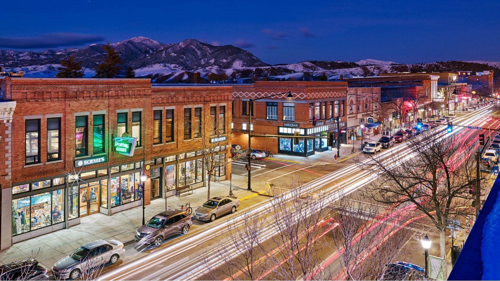 An aerial view of a city street at night with a mountain in the background.