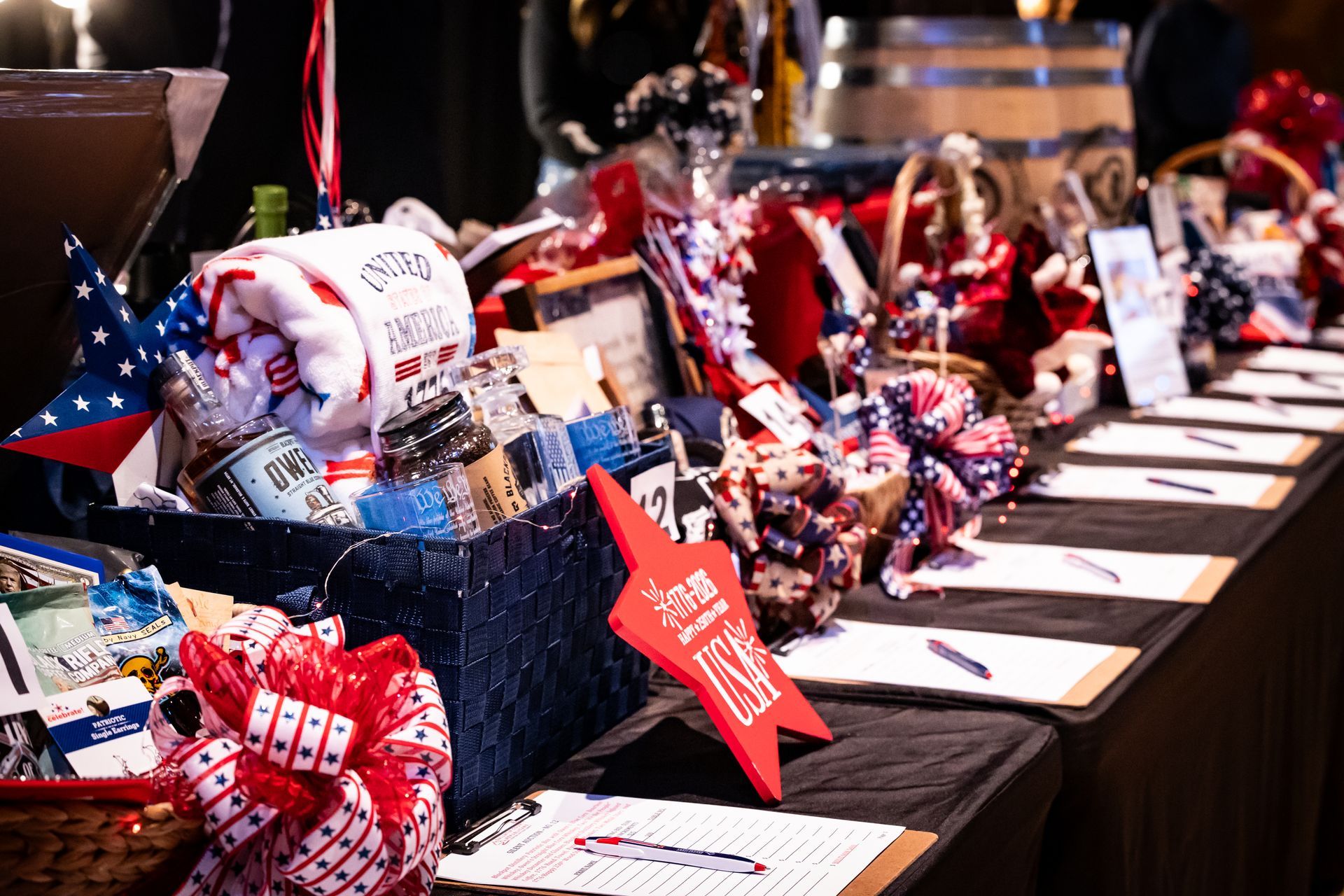 Table displays with patriotic gift baskets, red-white-blue decorations, and folded cards at an event booth.