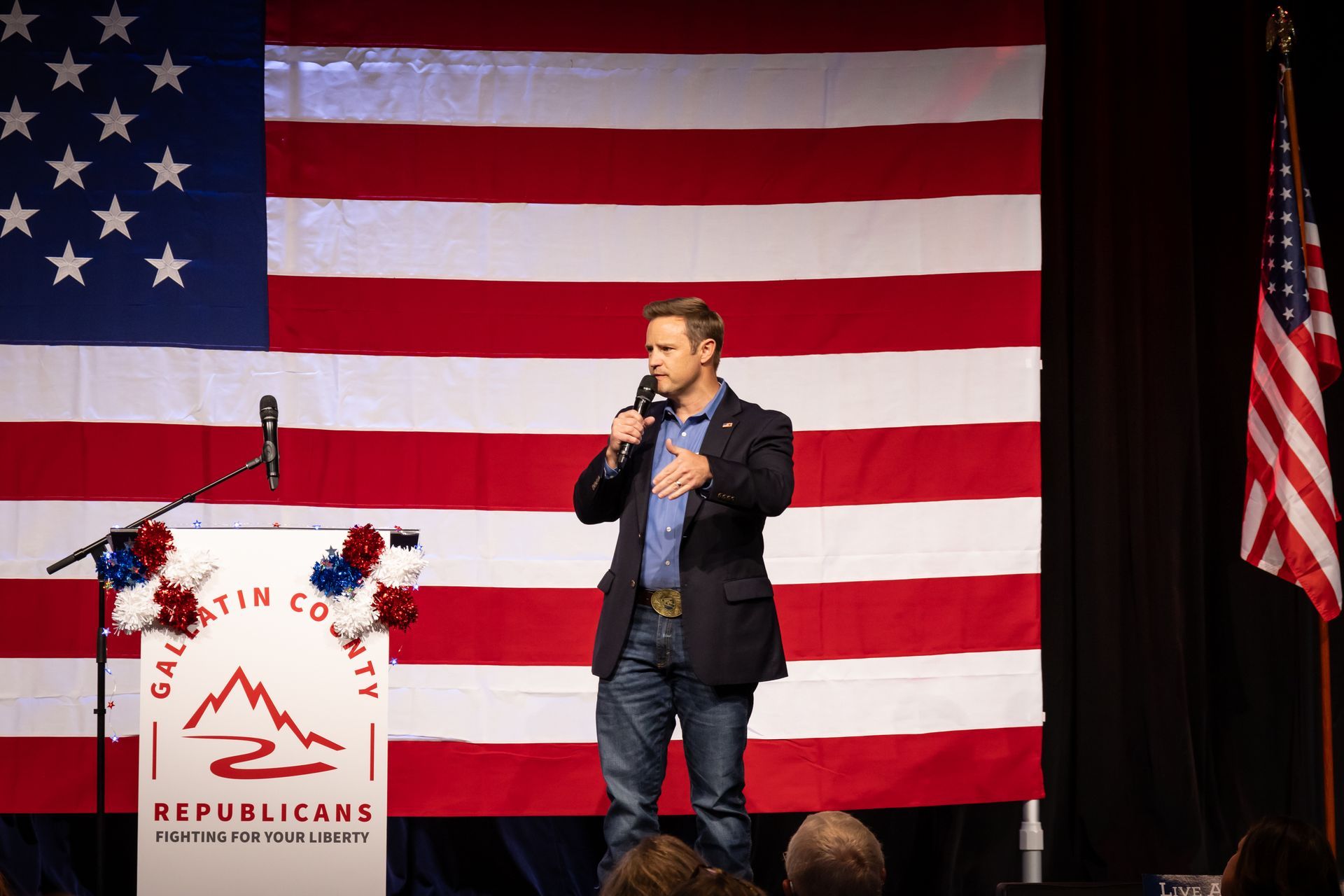 Speaker at podium before large American flag at a Republican event