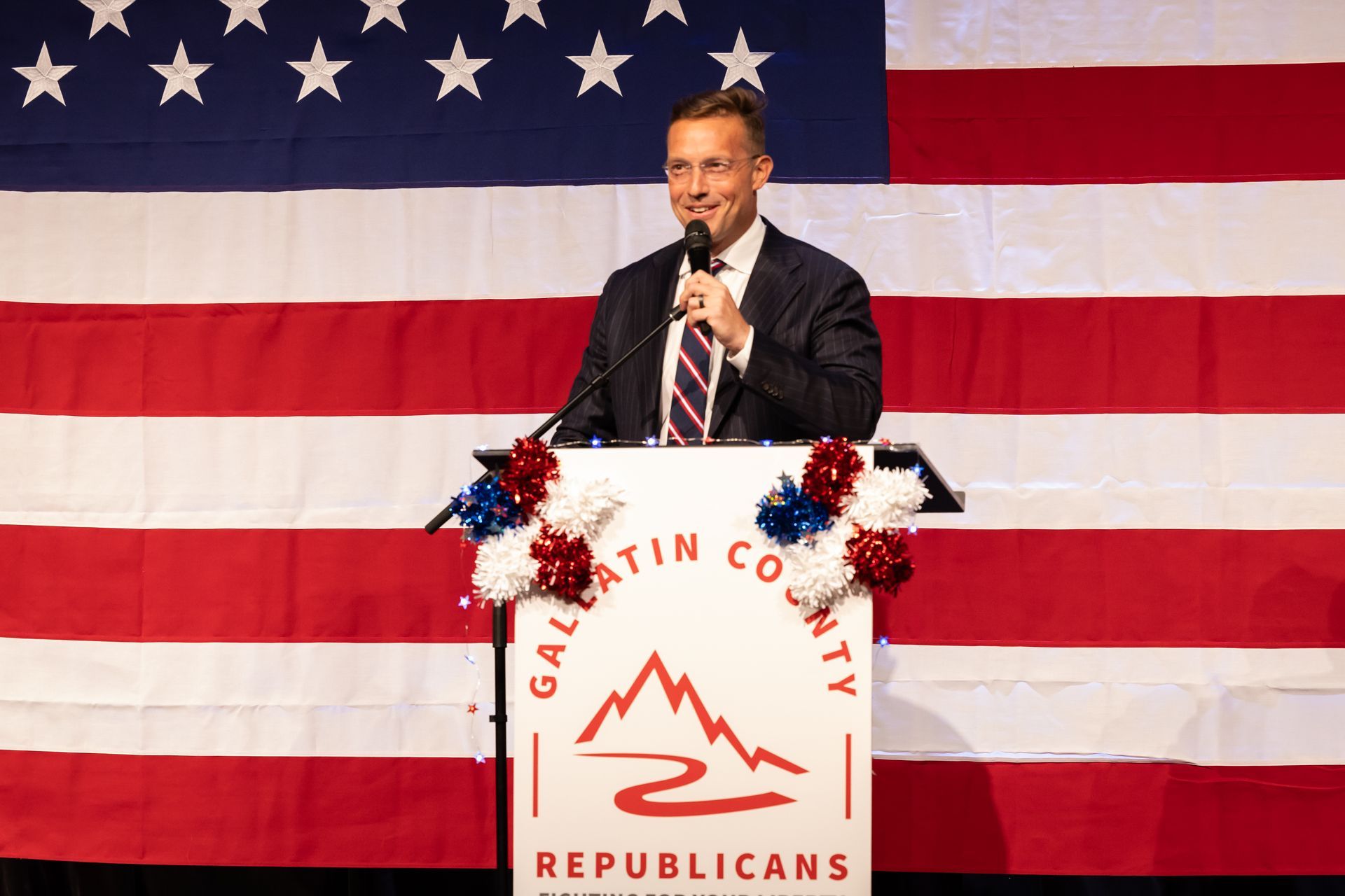 Speaker at podium with U.S. flag backdrop and “Gavin County Republicans” sign