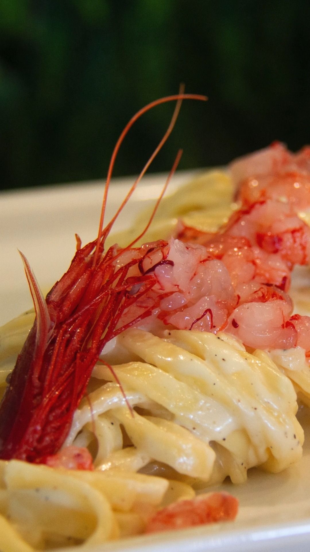 Primo piano di una cremosa pasta condita con peperoncino rosso e pezzetti di frutti di mare rosa.