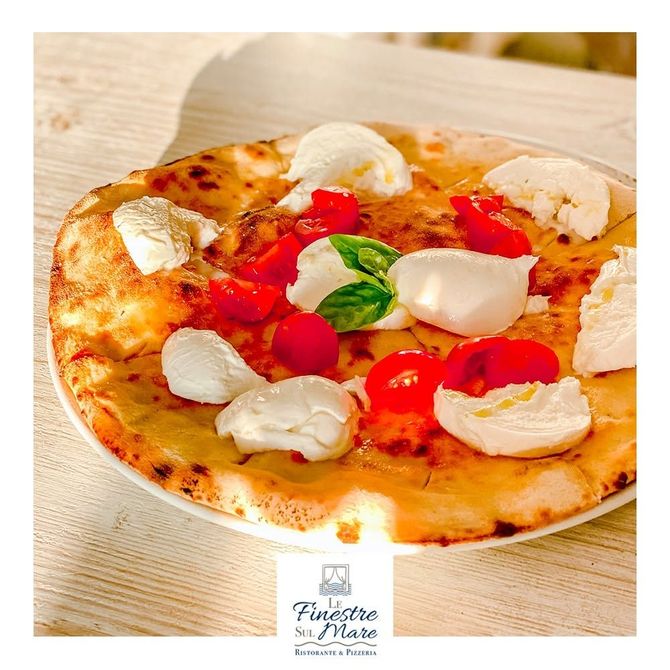 Pizza Margherita con mozzarella, pomodorini e basilico su un piatto bianco
