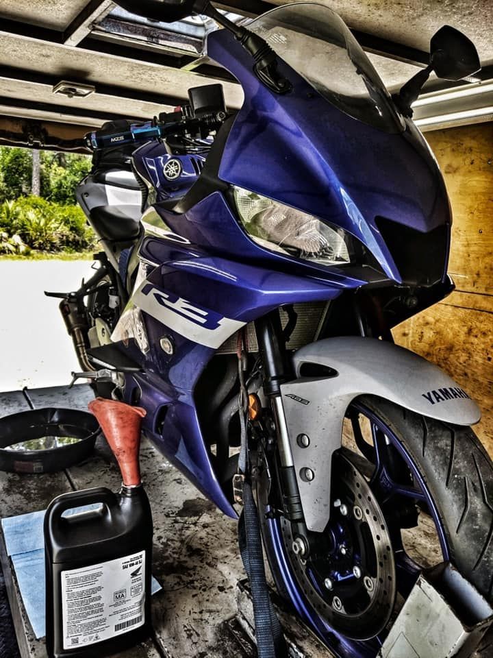 A blue motorcycle is parked in a garage next to a bottle of oil — St. Augustine, FL — Wide Open Mobile Tech