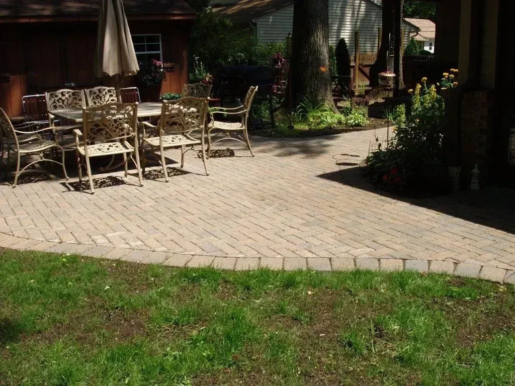 Brick patio with outdoor dining set and green grass.