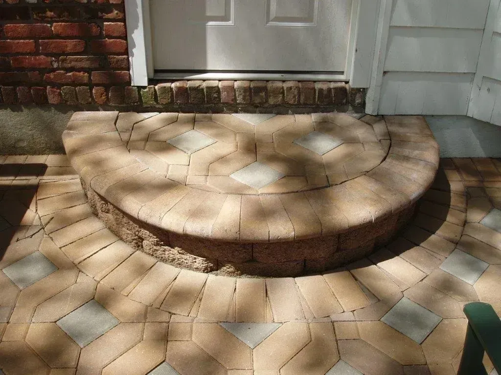 Brick paved half-circle step leading to a white door. The surrounding patio is also brick.