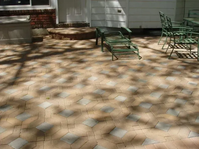 Brick patio with furniture and tree shadows.