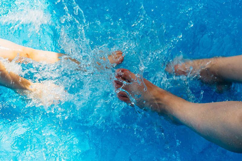 Swimmers’ arms and hands splashing in bright blue pool water during a race