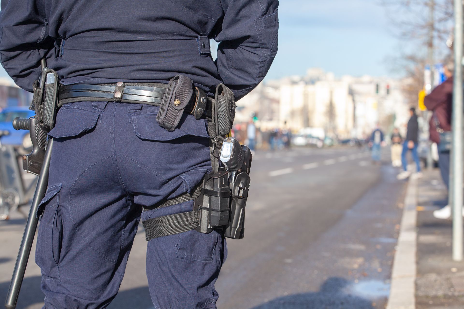 An armed security guard standing on a city street with a visible firearm holster.